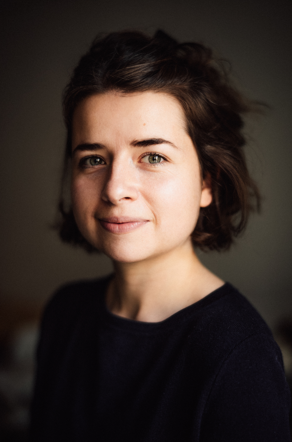 Portraitfotografie der Museologin und Bibliothekarin Linda Wößner im Halbprofil, grüne Augen, die braunen Haare halb zurückgebunden
